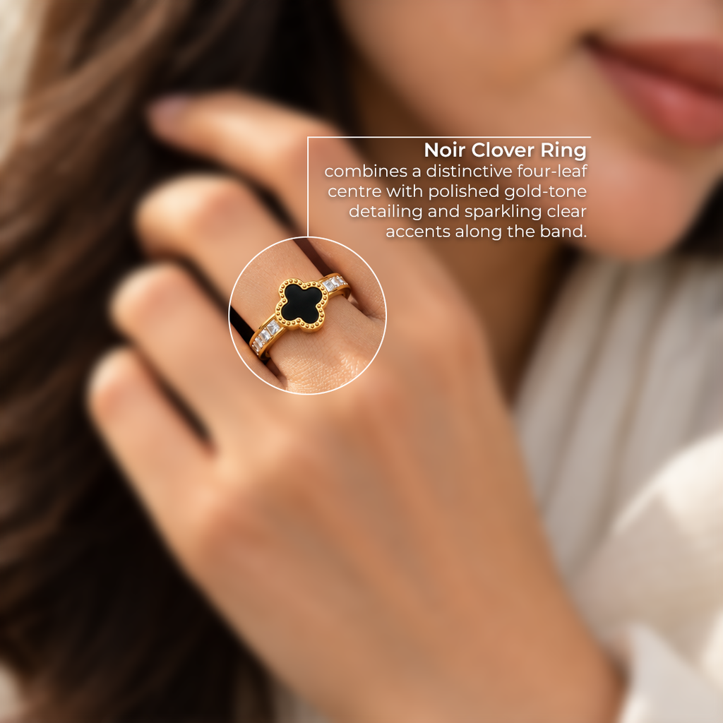 Close-up detail of the Noir Clover gold-tone ring featuring a black four-leaf clover center, polished gold-tone detailing, and clear sparkling accents on the band.