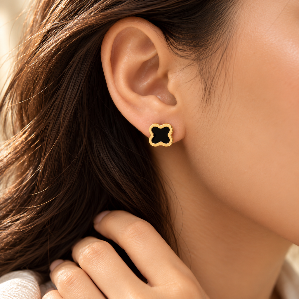 Woman wearing Noir Clover Stud Earrings featuring a black clover design with polished gold-tone detailing.