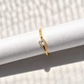 Gold-tone nose ring featuring a round clear stone detail, displayed on a white textured surface in natural light.